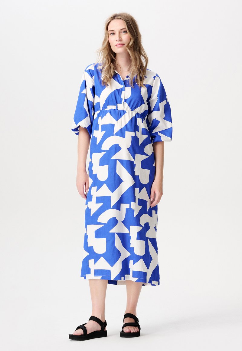 Blau-weißer, gemusterter Midikleid mit kurzen Ärmeln, lockerem Schnitt und gerafftem Bund, kombiniert mit schwarzen Sandalen.