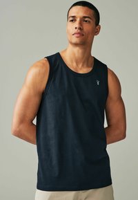 Navyblå tanktop i bomuld med rund halsudskæring og uden ærmer. Lille logo på brystet, glat tekstur.