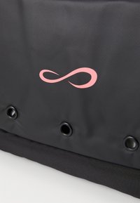 Tecido preto com um símbolo do infinito rosa acima de três ilhós de metal preto ao longo da borda.
