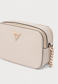 Μπεζ συνθετική τσάντα χιαστί με υφή, χρυσά μεταλλικά στοιχεία, διπλό φερμουάρ και αλυσίδα ως λουρί. Διαθέτει τριγωνικό λογότυπο ως διακοσμητικό στοιχείο.