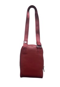 Borsa a tracolla rossa in pelle con forma rettangolare piatta, dotata di una tracolla in tessuto testurizzato e accenti metallici.