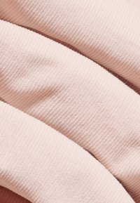 Blødt, ribbet stof i lys pink med subtil tekstur, der viser tre overlappende lag med glatte kanter og uden synlige mønstre eller accenter.