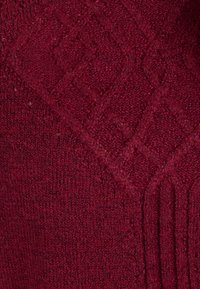 Tessuto a maglia bordeaux con motivi a diamante in rilievo e righe verticali. Texture morbida con un aspetto voluminoso, ideale per il calore.