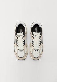 Αθλητικά παπούτσια με λευκό διχτυωτό υλικό και μπεζ σουέντ λεπτομέρειες, μαύρες πινελιές και λευκές κορδόνια. Ανάγλυφο σόλα και λογότυπο στο πλάι.