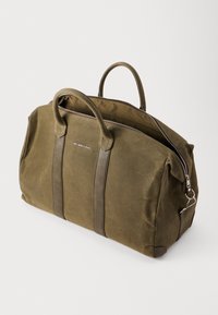 Olijfgroene canvas weekendtas met bruinleren accenten, dubbele handgrepen en een zilveren rits. Kenmerkt zich door een ruime, gestructureerde vormgeving.