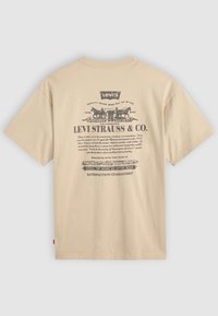 Beige kortermet T-skjorte med vintage-stil svart Levi Strauss & Co. logo og tekst trykket på ryggen.