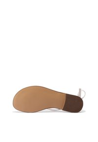 Sola piatta della scarpa con una finitura beige liscia, caratterizzata da una sezione in gomma marrone testurizzata sul tallone e un design minimalista.
