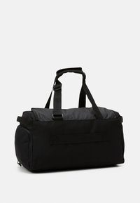 Black duffel bag made of durable fabric, featuring a top handle, adjustable shoulder strap, and a zippered closure. Compact cylindrical shape.