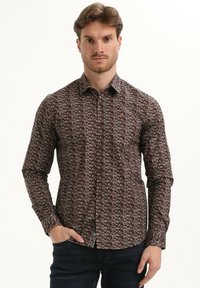 Bruine langetermijn shirt met een subtiel geometrisch patroon, knoopsrandkraag en klein logo op de borst. Katoenen stof met een normale pasvorm.