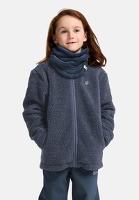 Giacca in pile blu navy con zip frontale, texture spessa e una sciarpa blu a girocollo. Presenta un piccolo logo sulla parte sinistra del petto.