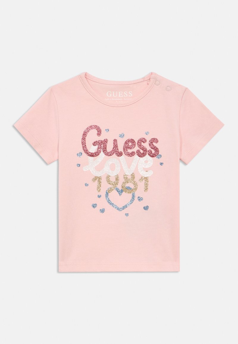 T-shirt à manches courtes rose pour tout-petit avec texte pailleté "Guess love 1981" et cœur bleu pailleté ainsi que de petits cœurs autour du motif.