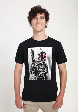 Czarna koszulka z graficznym wzorem przedstawiającym postać w hełmie z czerwonymi akcentami. Obrazek ma vintage'ową, zniszczoną teksturę.