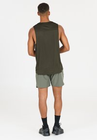 Olijfgroen zonder mouwen top gemaakt van ademend materiaal, gecombineerd met lichtgroene shorts. Zwarte schoenen en sokken maken de sportieve look compleet.