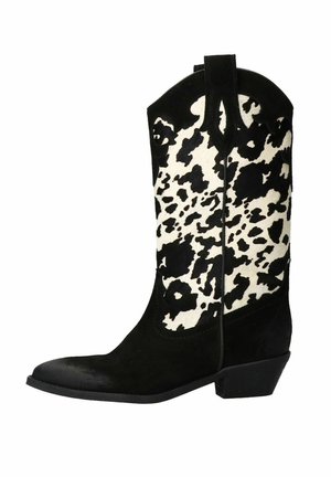 Black suede cowboy boot with a white and black cow print shaft, pointed toe, and a low block heel. Features stitching details and pull tabs.