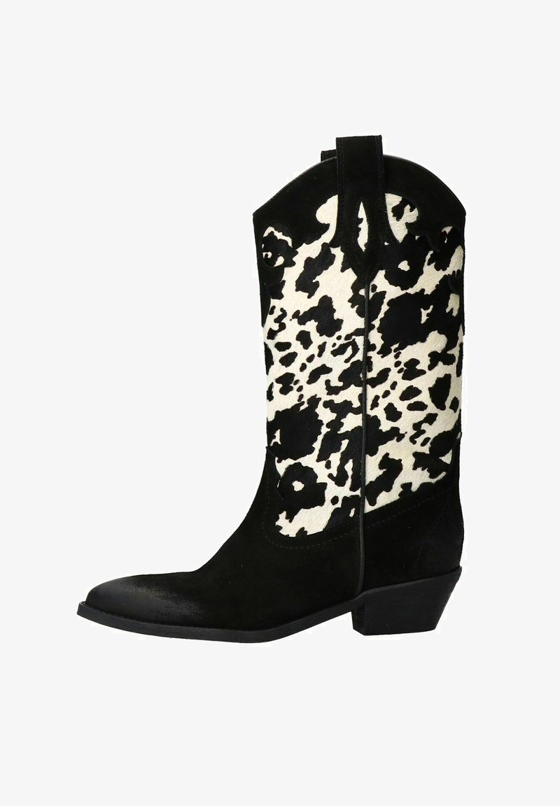 Botte de cowboy en suède noir avec une tige imprimée vache blanche et noire, bout pointu et petit talon en bloc. Présente des détails de couture et des languettes de tirage.