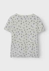 Weißes, geripptes T-Shirt mit kurzen Ärmeln, das ein florales Muster in Blau und Schwarz zeigt, einen gewellten Saum hat und einen Rundhalsausschnitt aufweist.