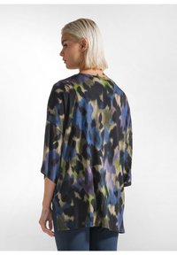 Top ampio con un motivo animalier multicolore, che presenta diverse tonalità di blu, verde e nero. Tessuto morbido con spalle scese e maniche corte.