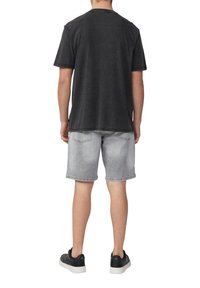 Schwarzes strukturiertes kurzärmliges Hemd, lockere Passform, kombiniert mit hellgrauen Denim-Shorts und schwarzen Sneakers. Einfaches Design, keine sichtbaren Muster.