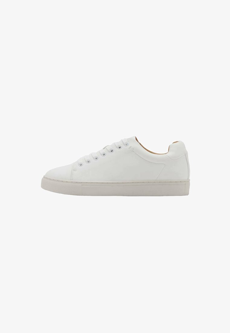 Zapatilla blanca con parte superior de cuero liso, puntera redonda y seis ojales. Cuenta con suela plana de goma y diseño minimalista sin logotipos visibles.