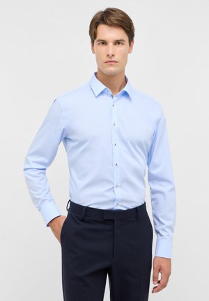 Camicia azzurra a maniche lunghe con colletto classico, caratterizzata da una texture liscia e bottoni argentati lungo il davanti.