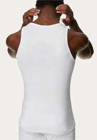 White fitted tank top with a round neckline, smooth texture, and no visible patterns or hardware, viewed from the back.