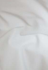 Biała bawełniana tkanina o gładkiej fakturze, z delikatnymi fałdami i zmarszczkami, tworząca miękki, płynący wygląd.