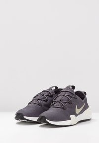 Mörkgrå träningsskor i mesh-material med vita sulor, med en slimmad design, snörning och en subtil logotypdetalj.