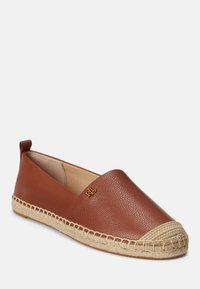 Brown leather slip-on shoe with a textured finish, jute rope trim, and a gold logo accent on the side. Rounded toe design.