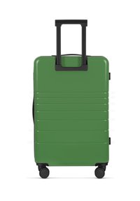 Grüner Hartschalenkoffer mit strukturiertem, geripptem Oberflächen, ausziehbarem schwarzen Griff und vier schwarzen Rädern für die Mobilität.