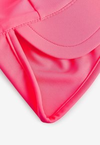 Cappello rosa brillante realizzato in tessuto liscio, con una visiera arrotondata e dettagli di cucitura visibili lungo i bordi.