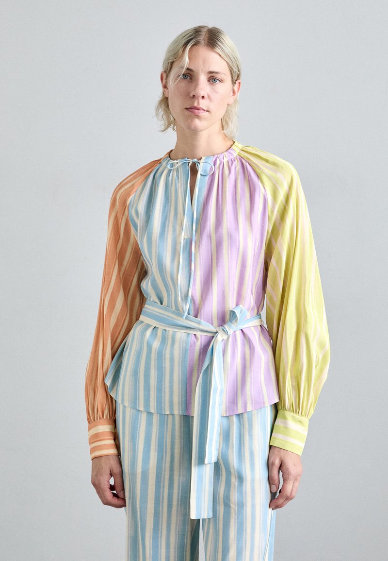 Multicolored striped blouse with long sleeves, featuring a tied waist and a round neckline. Colors include peach, blue, lavender, and green.