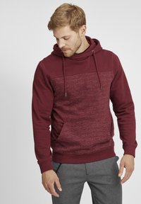 Felpa con cappuccio bordeaux con pannello frontale texturizzato, cordini e tasca a marsupio. Tessuto morbido con polsini a costine.