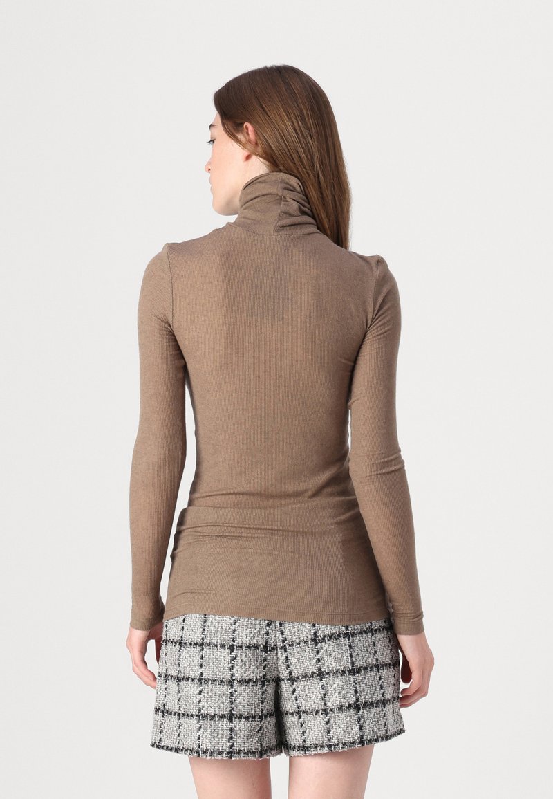 Brauner, gerippter Rollkragenpullover mit langen Ärmeln, kombiniert mit strukturierten Karoshorts in Grau und Schwarz, die eine enge Passform und nahtloses Design zeigen.