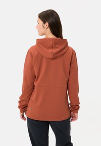 Hoodie di colore ruggine con una texture morbida, dotato di cappuccio, maniche lunghe e un design semplice. Cucitura sul retro con un dettaglio accentato sottile.