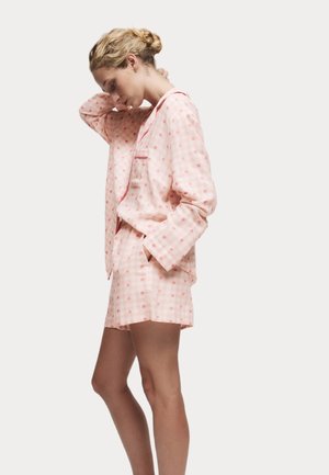 Kort pyjamas i rosa rutigt mönster gjord av lättviktsmaterial, med en knapp-upprad top med en ficka och matchande shorts.