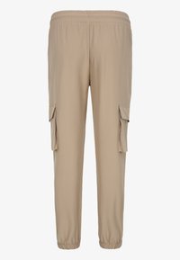 Pantalon cargo beige avec taille et poignets élastiques, doté de poches latérales à rabat sur les deux jambes.