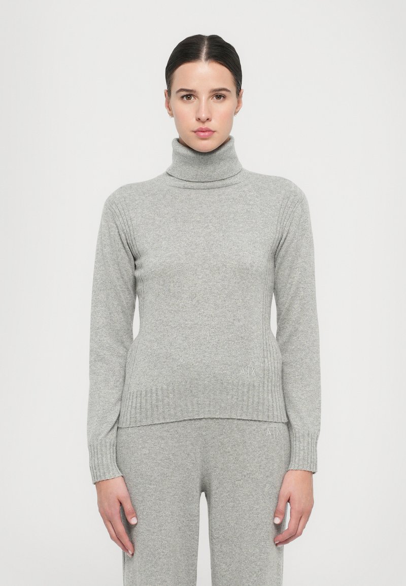 Grauer Rollkragenpullover aus einem weichen Strickstoff. Mit gerippten Akzenten am Kragen und an den Bündchen. Schlichte, figurbetonte Silhouette.