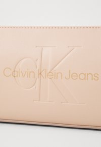 Novčanik Calvin Klein Jeans od mekanog ružičastog sintetičkog materijala. Sadrži utisnuti logotip i glatku teksturu s kontrastnim zlatnim natpisom.