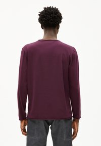 Paarse longsleeve shirt van zachte stof. Ronde hals, losse pasvorm, met een gladde textuur. Weergave van de achterkant die de halslijn en de mouwen toont.