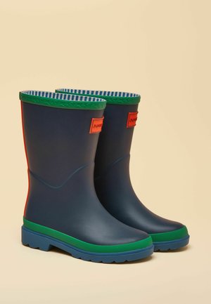 Tmavomodré gumové dážďové čižmy so zeleným lemom a podrážkami, prúžkovaná vnútorná podšívka a oranžové obdĺžnikové logo na prednej strane.