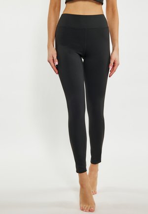 Schwarze Leggings mit hohem Bund, glatter Textur und taillierter Passform. Verfügt über einen bodenlangen Schnitt und minimale Nähte.