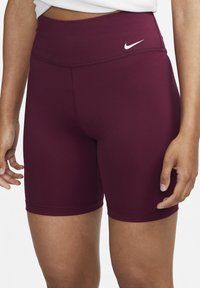 Bordeauxkleurige rekbare sportbroekjes met een hoge taille en subtiele stiksels, met een klein wit Nike-logo aan de voorkant.