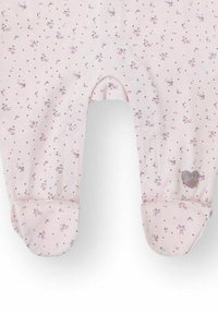 Pijama rosa para bebé con pies, estampado con pequeñas flores moradas y botones a presión en la parte delantera y las piernas, con un parche en forma de corazón.