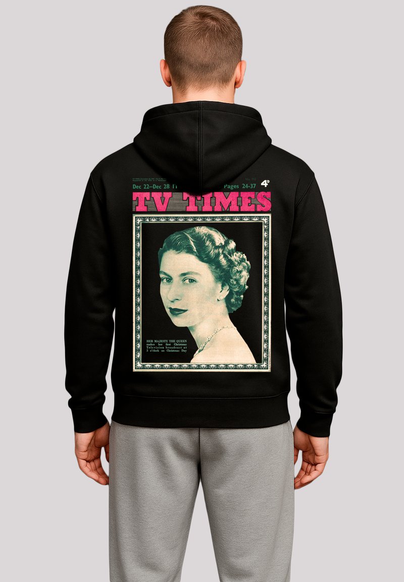 Schwarzer Hoodie mit einem grafischen Motiv der Retro-Zeitschrift TV Times, das ein Porträt, einen dekorativen Rand und pinken Text darüber zeigt. Graue Sweatpants sind darunter sichtbar.