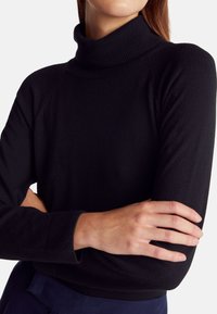 Czarny, dopasowany sweter z golfem wykonany z miękkiego materiału, z prążkowanymi mankietami i dekoltem. Charakteryzuje się prostym designem i gładką fakturą.