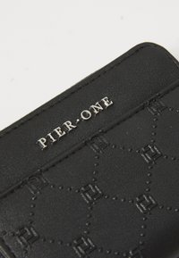 Black faux leather wallet featuring a debossed geometric pattern and silver "PIER ONE" logo. Textured surface with contrasting accents.