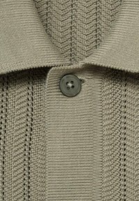 Strickpullover in Hellgrau mit einem strukturierten Muster aus vertikalen Streifen. Verfügt über einen Kragen und einen schwarzen Knopf in der Nähe des Halsausschnitts.