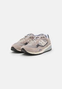 Scarpe sportive beige con una combinazione di camoscio e mesh, punta rotonda, collo imbottito, chiusura con lacci e suola in gomma nera.