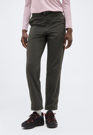 Personne portant un pantalon droit vert foncé, un haut à manches longues rose clair, des chaussettes blanches et des chaussures de randonnée noires avec des lacets rouges.