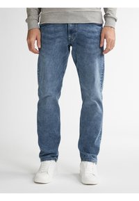 Jeans in denim azzurro chiaro con vestibilità dritta, con leggere pieghe e vita a media altezza, abbinati a sneakers bianche.
